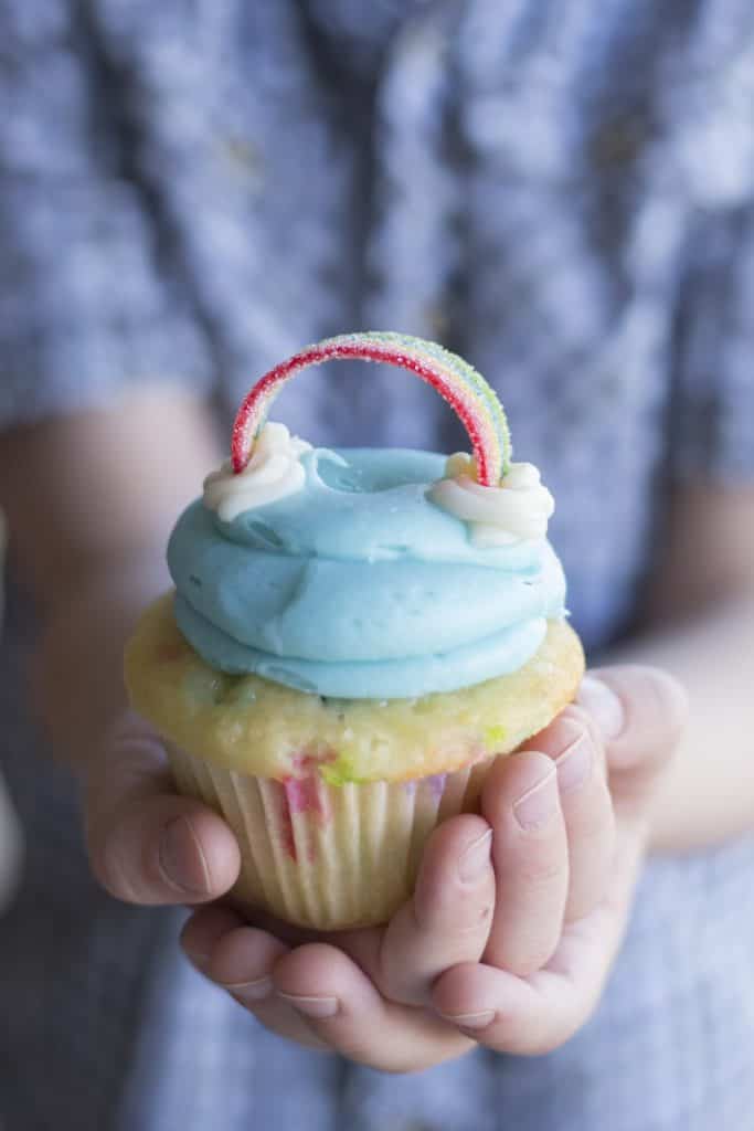 close up of a cuplcake with a cloud and candy rainbow.