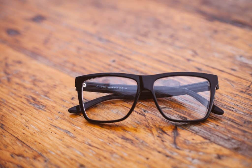 Blacked framed glasses sitting on a wooden desktop