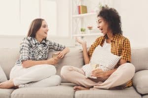 Happy female friends chatting and drinking wine at home. Two young women having friendly talk, gossiping and celebrating new life, slumber party, copy space