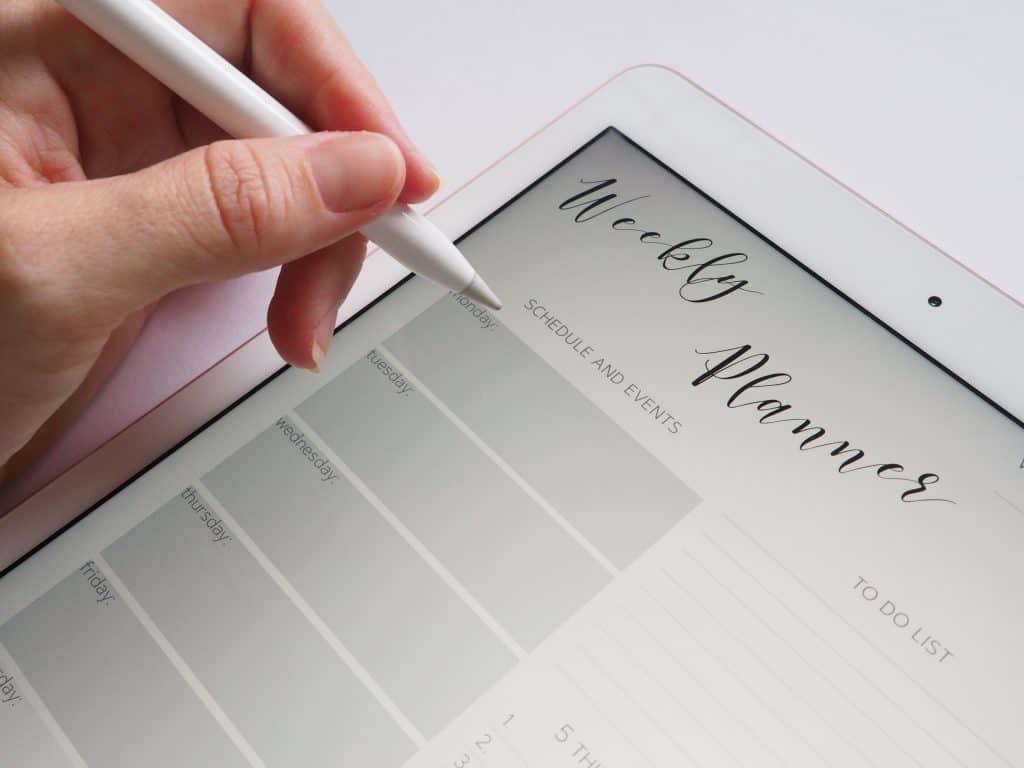 Close up of hand holding a stylus writing on a tablet.