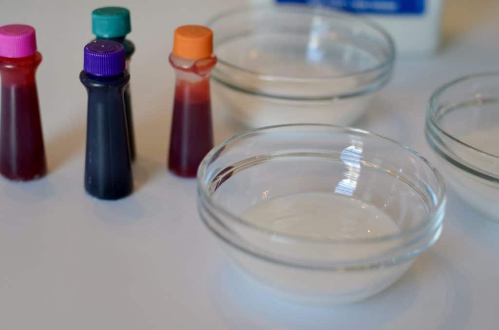 Food coloring next to small bowls of glue