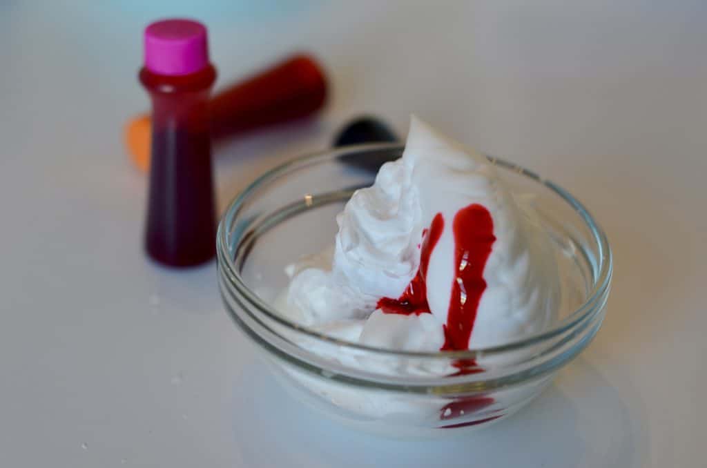 Food coloring drizzeled on shaving cream in a small bowl