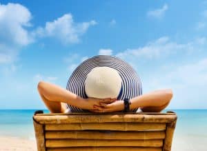 Woman Living The Dream laying out at the beach with her hands behind her head.