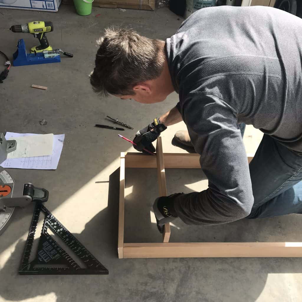 Handsome man testing the fit of shelf in the frame.