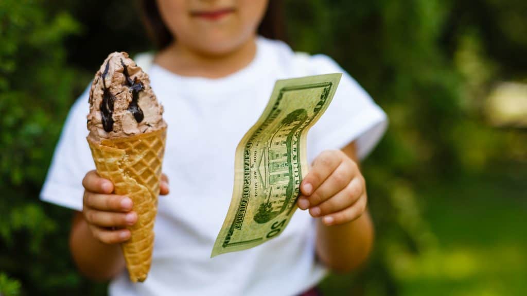 Little girl exchanging ice cream for dollar