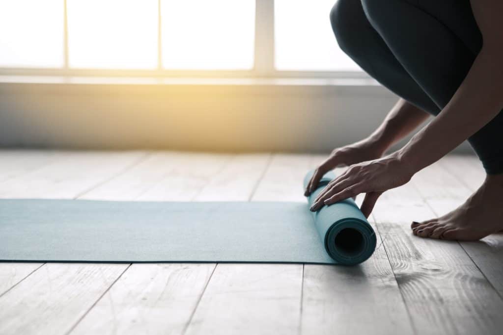 Mom doing yoga rolling mat indoors near window