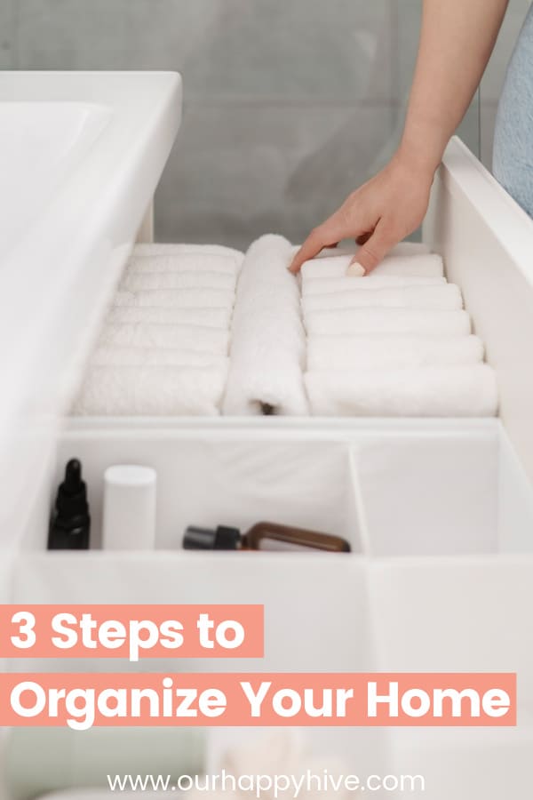 An organized bathrroom drawer with white wash cloths and text 3 steps to an organized home.