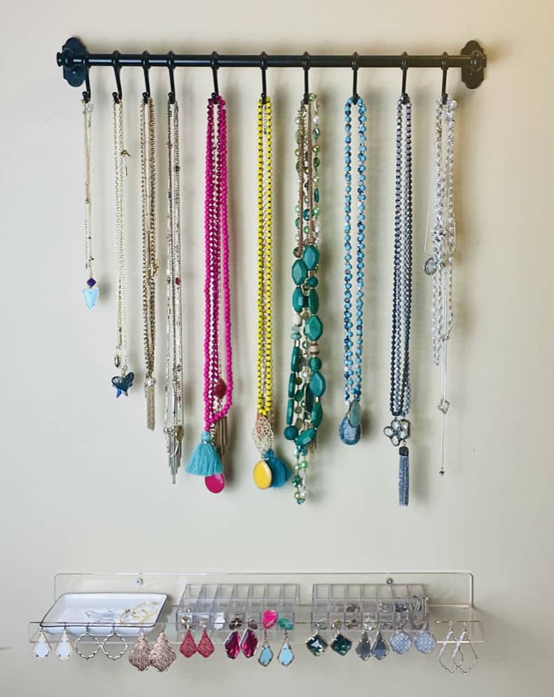 DIY Jewelry station with necklaces hanging on a bar and an acrylic shelf to organize earrings and rings in this organized closet.