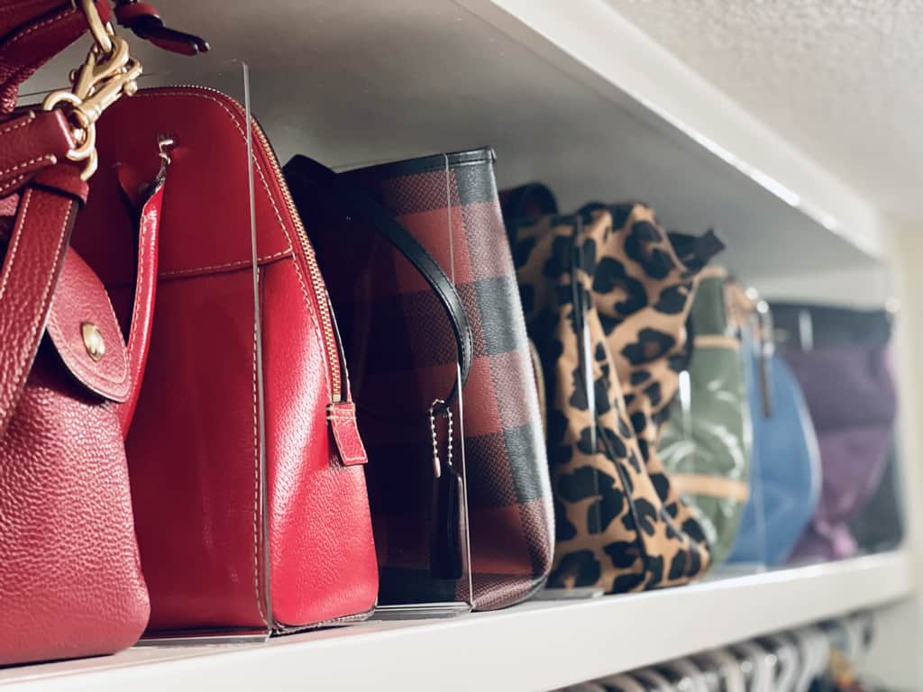 Organized closet ideas with handbags organized on the top shelf with acrylic dividers.