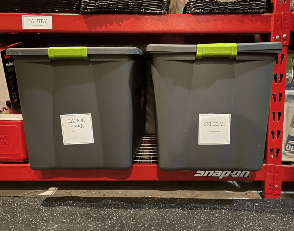 Two bins are used to contain like items after decluttering and organiziing a spacce. The image shows bins for canoe gear and ski gear.