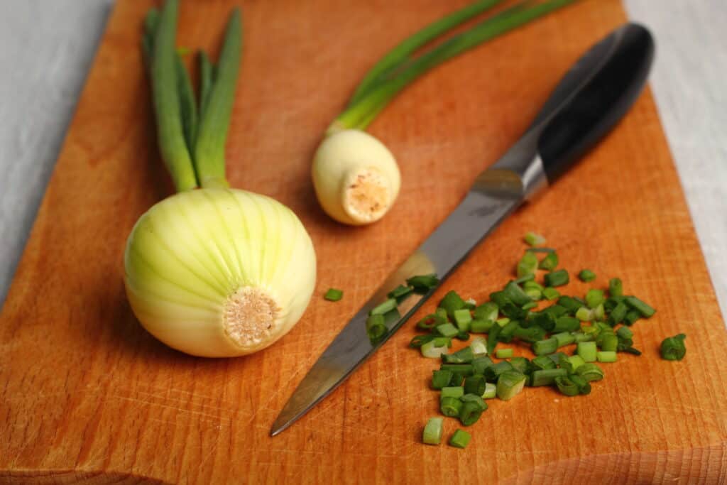 Green onions on a chopping board being prepared for thanksgiving dinner recipe.