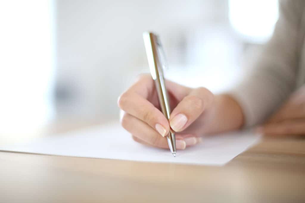 close up of a woman's hand writing down her decluttering goals