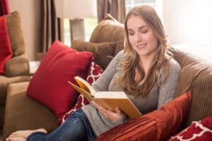 Woman sitting on the couch reading home organization and decluttering books