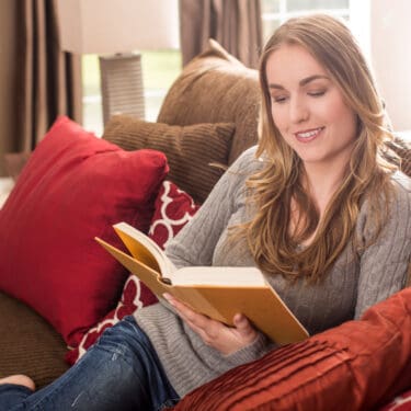 Woman sitting on the couch reading home organization and decluttering books