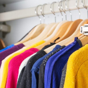 decluttered closet with sweaters neatly hanging up