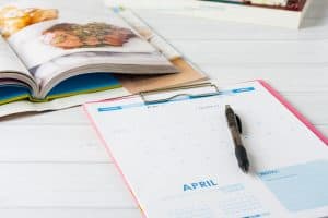 Monthly calendar and stack of cookbooks. Conceptual image showing meal planning in progress.