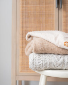 Sweaters folded and stacked in an organized home.