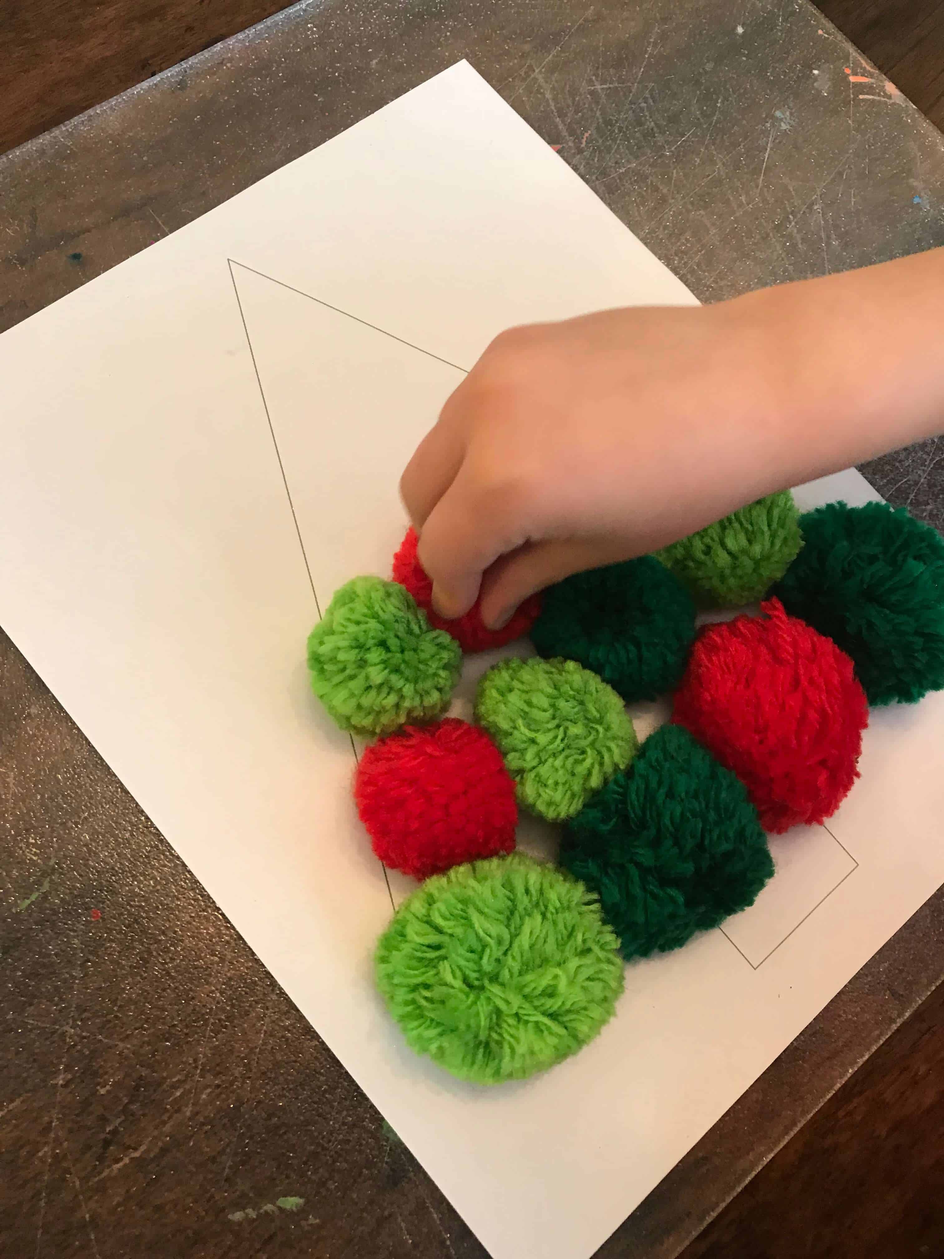 Kid creating a pom pom christmas tree