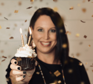 Girl holding a cupcake with two candles on it.