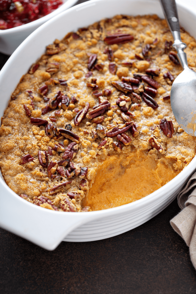 Close up picture of a sweet potato cassarole with toasted pecans and brown sugar crumble on top.  This dish was made in advance, one step to having a stress-free holiday meal.