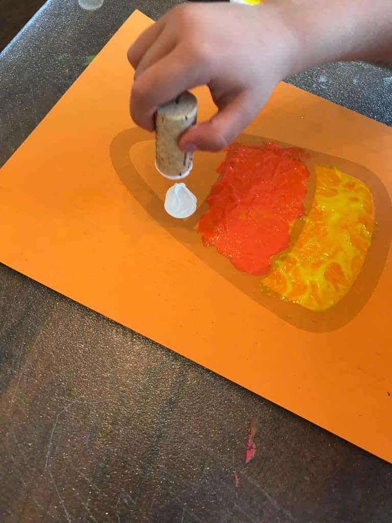 Candy Corn Printable being painted by a preschooler with a wine cork stamp.