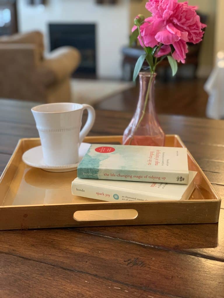 coffee cup with the life changing magic of tidying up book and a flower sitting next to it on top of a table