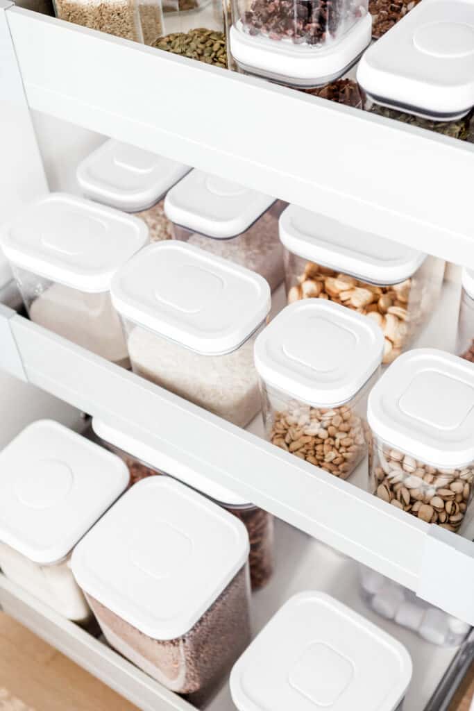 top down view of bulk storage containers in a drawer with white lids and clear bins to help you organize your pantry.