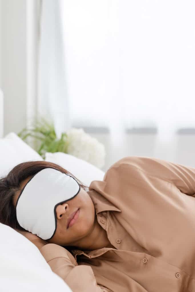 A woman sleeping with a mask on as she rest so that she can be more productive with less stress.