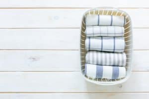 Marie Kondo tidying - folded kitchen linens in white basket, top view