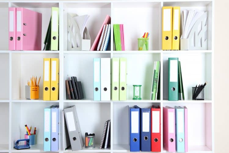 White office shelves with folders and different stationery, close up