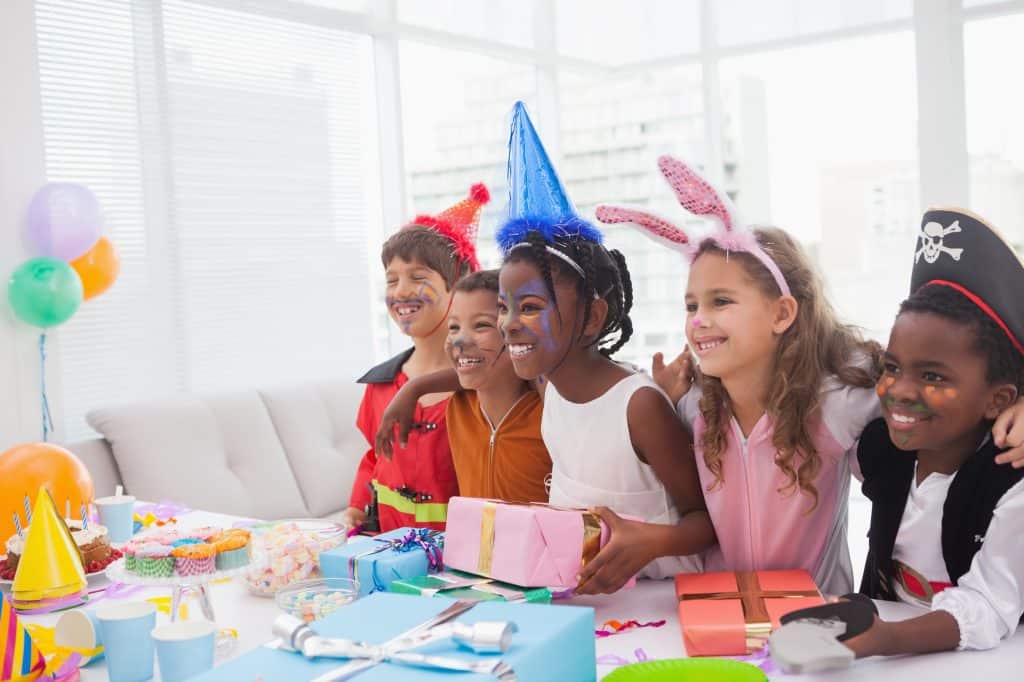 Happy children at fancy dress birthday party at home in the living room