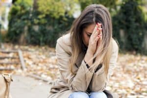 Frustrated woman sits with her head in her hands.