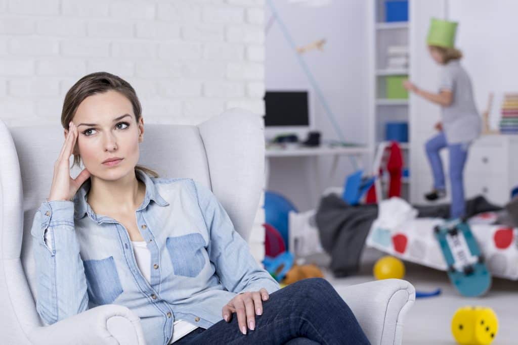 frustrated mom sits in chair while child misbehaves