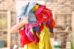 Woman holding pile of colorful clothes indoors