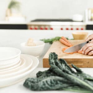 grocery items on the counter with a woman cutting carrots